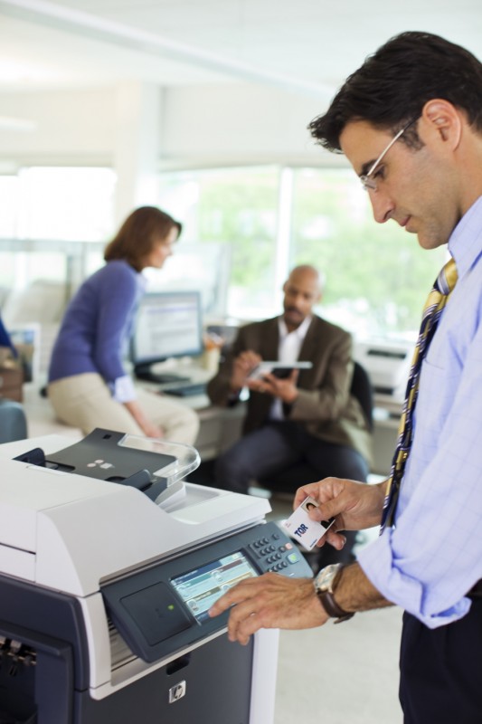 Man holding secure access card to card reader on HP Color LaserJet