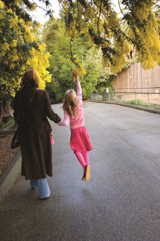 Mother and daughter walking under yellow tree